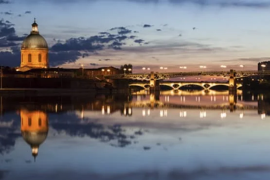 circuit touristique vtc toulouse canal du midi Pont illuminé et son reflet sur l’eau au crépuscule.